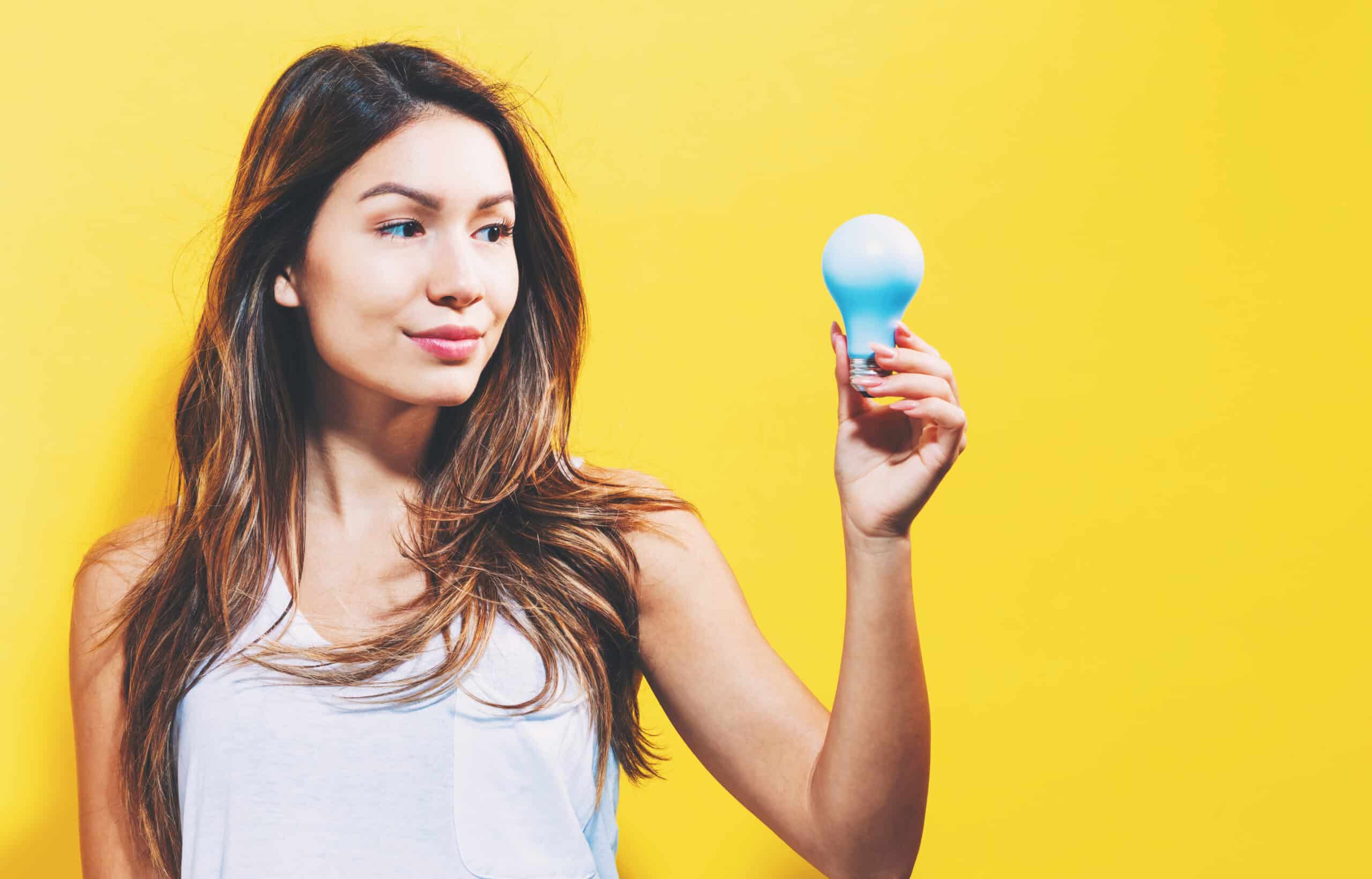 Graphicstock young woman holding a light bulb on a yellow background rwrxu3vdz scaled
